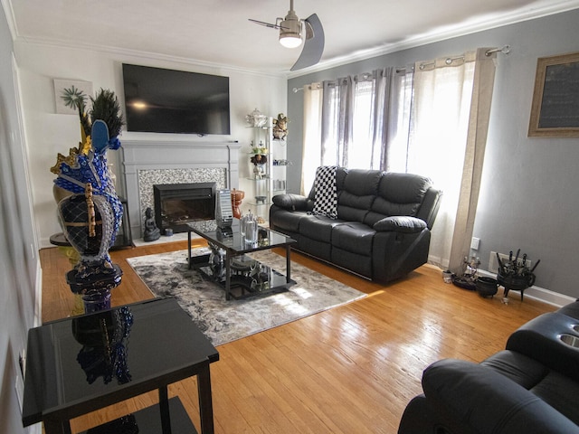 living room with a fireplace, crown molding, wood-type flooring, and ceiling fan