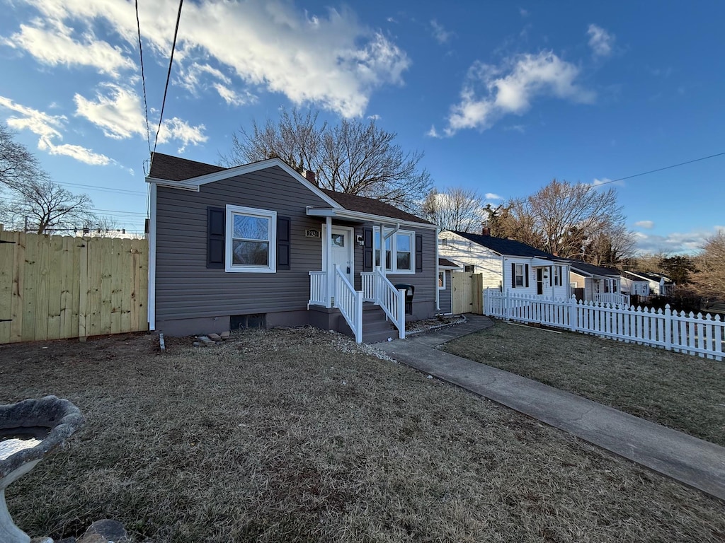 bungalow-style home with a front yard and fence private yard