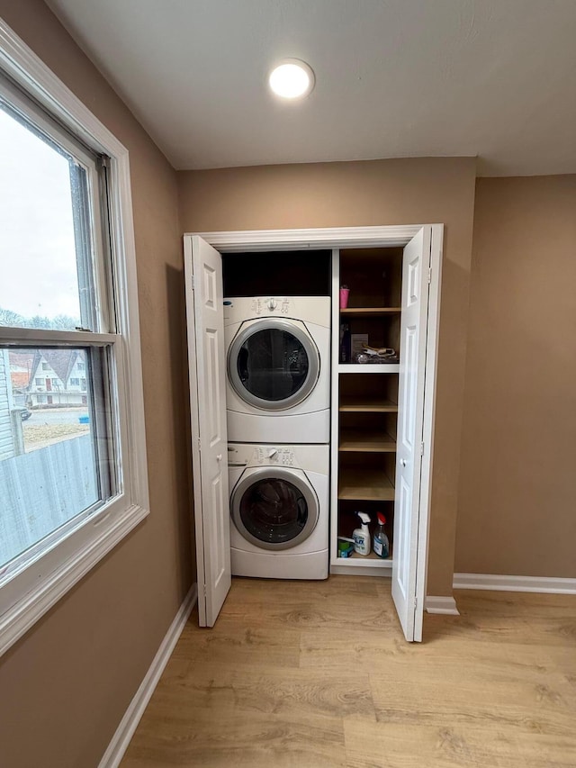 washroom featuring light hardwood / wood-style flooring and stacked washer and clothes dryer