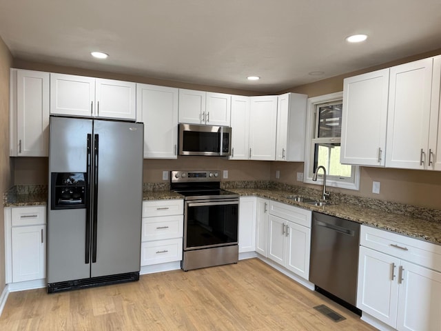 kitchen featuring white cabinetry, stainless steel appliances, sink, and dark stone counters