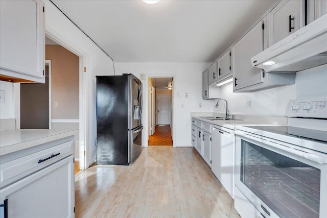 kitchen with white cabinetry, sink, white appliances, and light hardwood / wood-style floors