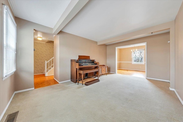 misc room with an inviting chandelier, carpet flooring, and beam ceiling