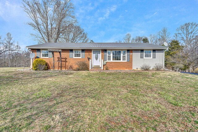 ranch-style house featuring brick siding, driveway, metal roof, and a front lawn