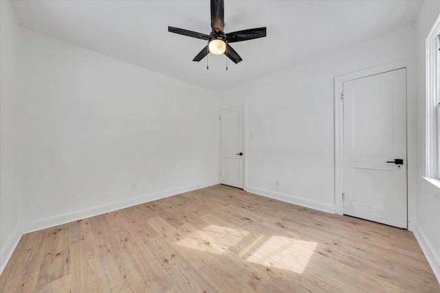 unfurnished room with light wood-type flooring, a ceiling fan, and baseboards