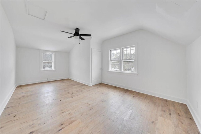 additional living space with baseboards, vaulted ceiling, and light wood finished floors