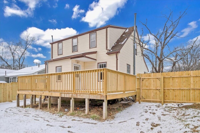 snow covered back of property featuring fence and a deck