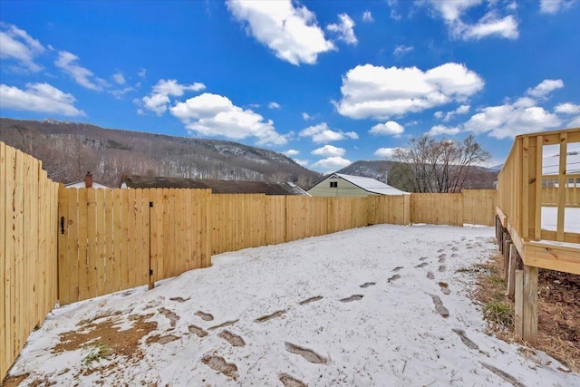 yard covered in snow featuring a fenced backyard and a mountain view