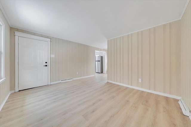 spare room featuring a baseboard heating unit, light wood-type flooring, and baseboards