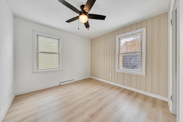 spare room with light wood-type flooring, baseboards, and a ceiling fan