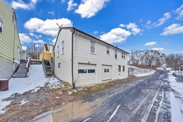 view of snowy exterior with a garage and stairs