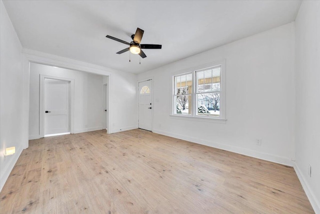 spare room featuring light wood finished floors, baseboards, and a ceiling fan