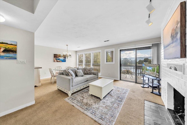 carpeted living room featuring rail lighting, a chandelier, and a brick fireplace