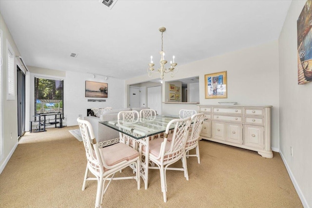 dining space featuring an inviting chandelier, light colored carpet, and rail lighting