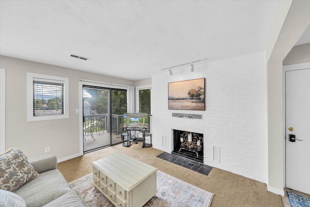 living room featuring carpet flooring, rail lighting, and a brick fireplace