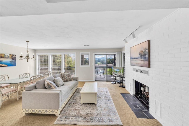 carpeted living room featuring a brick fireplace, track lighting, and a notable chandelier