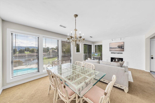 carpeted dining room featuring a fireplace and a chandelier