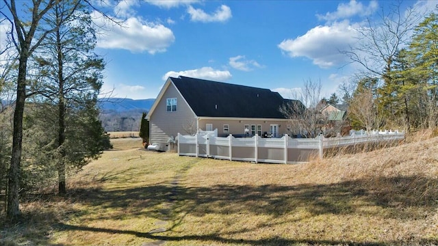 back of house featuring a mountain view and a lawn