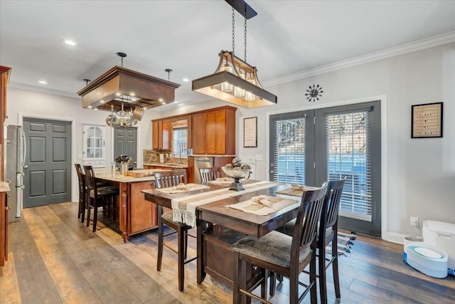 dining space featuring wood-type flooring, a healthy amount of sunlight, and crown molding