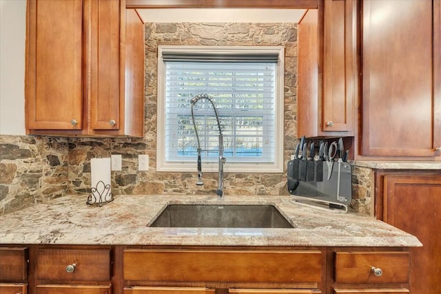 kitchen featuring light stone counters, sink, and tasteful backsplash