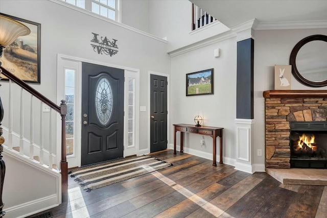 foyer with crown molding, a fireplace, dark hardwood / wood-style flooring, and a high ceiling