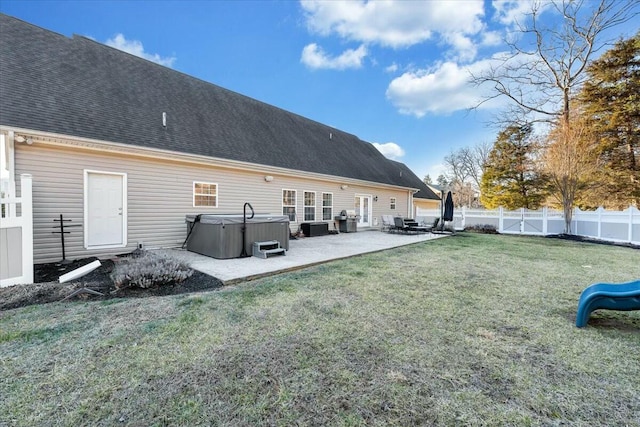 back of house with a yard, a patio area, and a hot tub