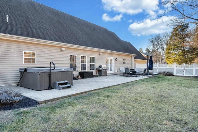 rear view of property featuring a lawn, a hot tub, and a patio