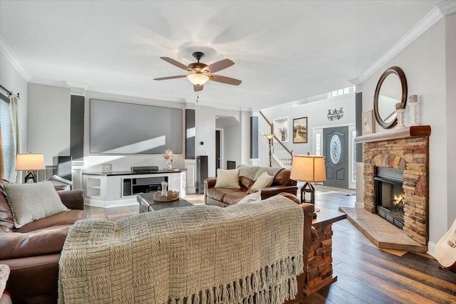 living room featuring crown molding, wood-type flooring, ceiling fan, and a fireplace