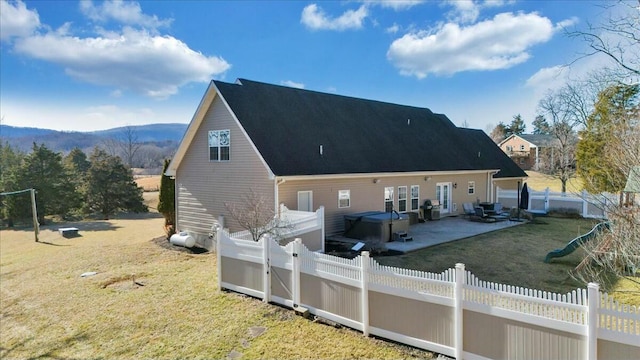 back of property with a yard, a hot tub, a mountain view, and a patio