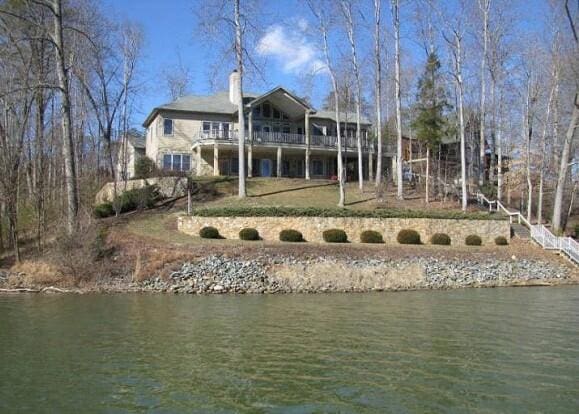 back of house with a water view and a chimney