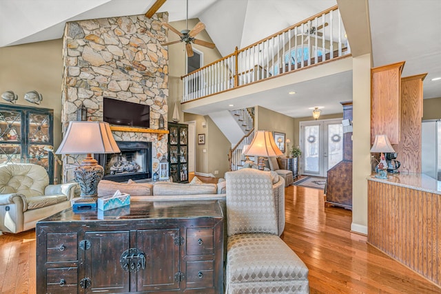 living area featuring wood-type flooring, a ceiling fan, a fireplace, and stairway