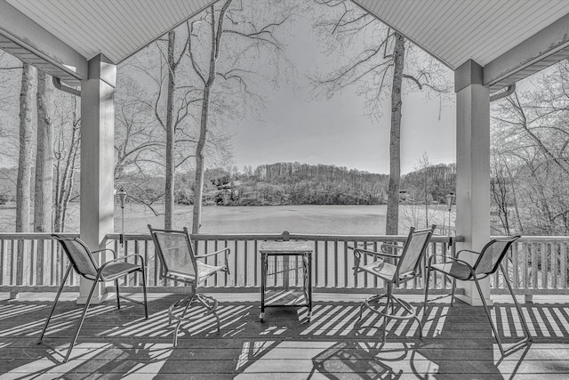 wooden terrace with a view of trees and covered porch