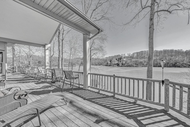 wooden terrace featuring a porch, a water view, and a forest view