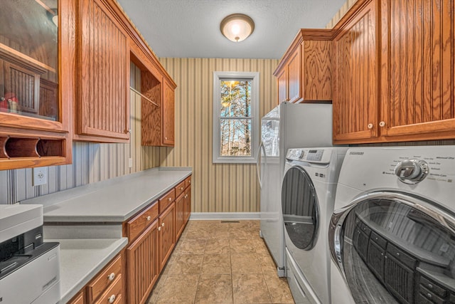 laundry room with washer and dryer, baseboards, wallpapered walls, a textured ceiling, and cabinet space