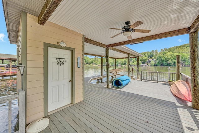 wooden terrace featuring a water view, ceiling fan, and a boat dock