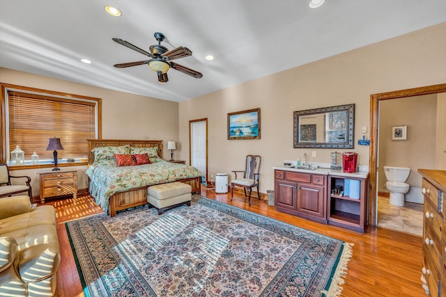 bedroom with a sink, light wood finished floors, recessed lighting, baseboards, and wet bar
