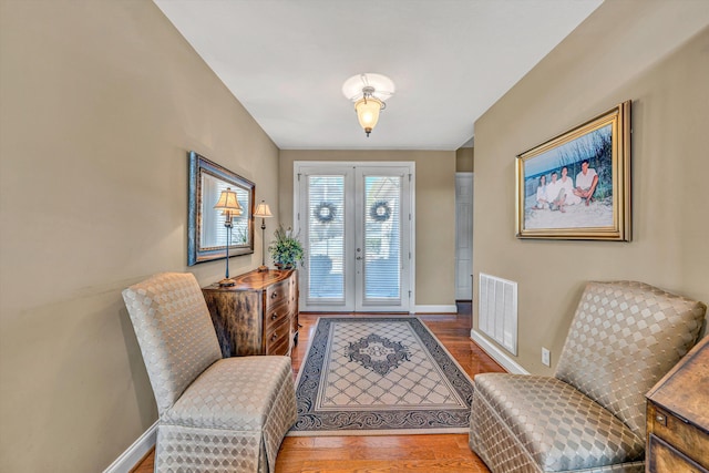 interior space featuring french doors, baseboards, wood finished floors, and visible vents