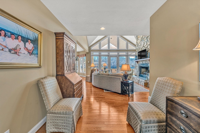 living room with baseboards, vaulted ceiling, light wood finished floors, and a fireplace