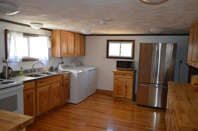 kitchen featuring light wood-style flooring, stainless steel appliances, washer and dryer, wooden counters, and a sink