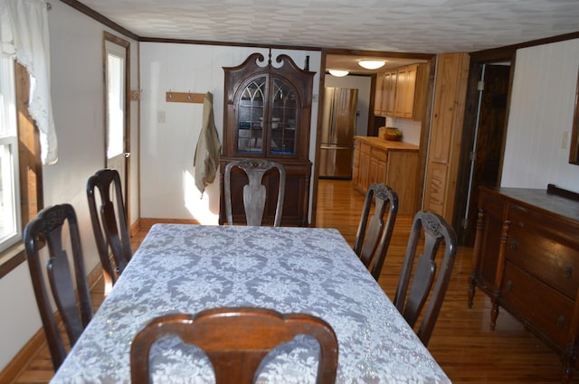 dining area featuring crown molding, baseboards, and wood finished floors