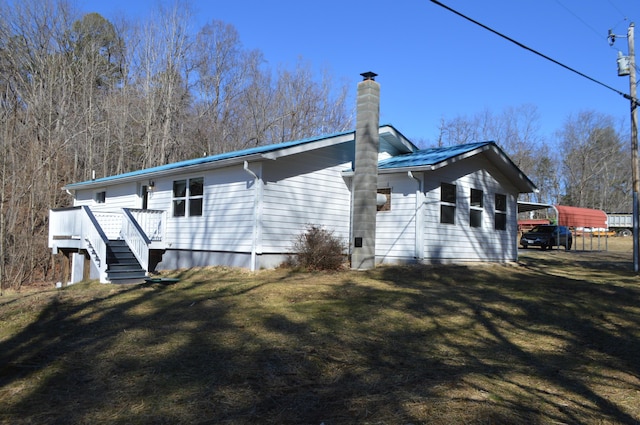 exterior space featuring a lawn, a chimney, and a wooden deck