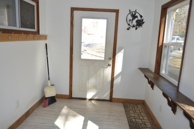 doorway featuring baseboards, plenty of natural light, and light wood finished floors