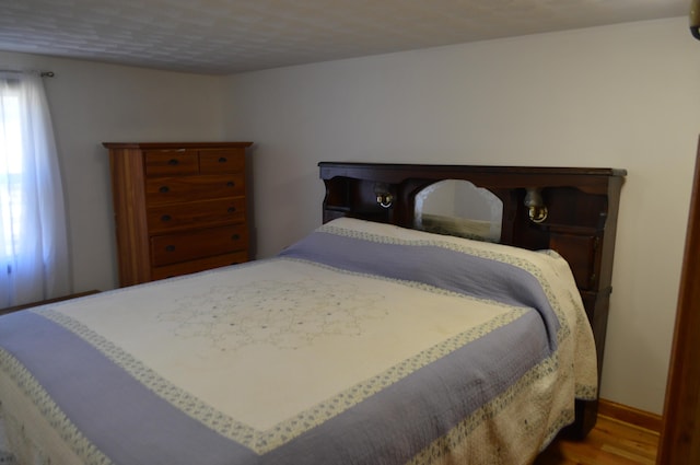 bedroom with baseboards and wood finished floors