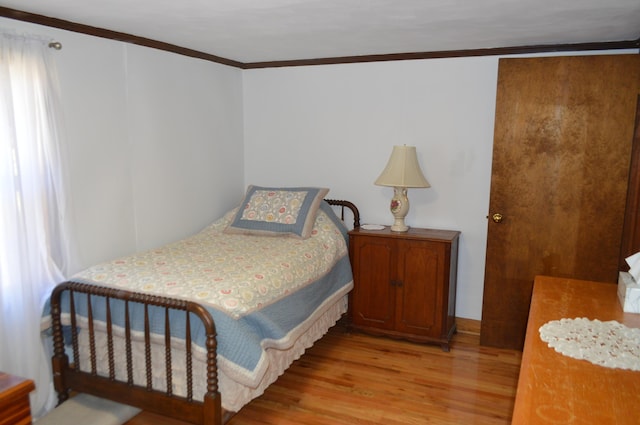 bedroom featuring crown molding and light wood-style flooring