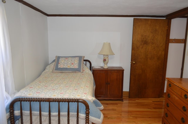 bedroom featuring light wood-style flooring and crown molding