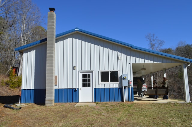 view of property exterior with a carport, a lawn, a chimney, and board and batten siding