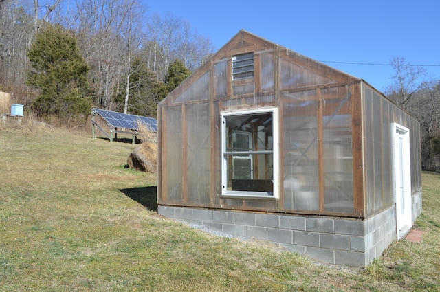 view of greenhouse featuring a yard and solar panels