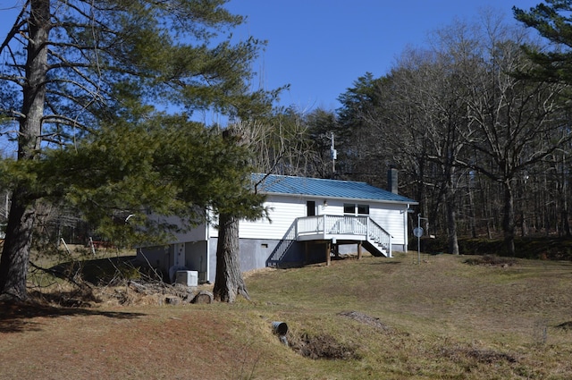 exterior space with a standing seam roof, central AC, and metal roof