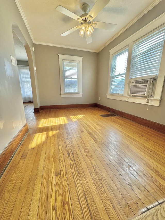 unfurnished room featuring cooling unit, ornamental molding, ceiling fan, and light wood-type flooring