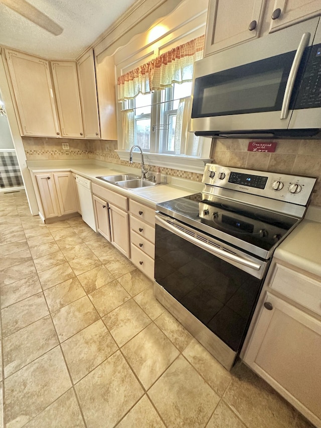 kitchen with sink, a textured ceiling, appliances with stainless steel finishes, cream cabinets, and decorative backsplash