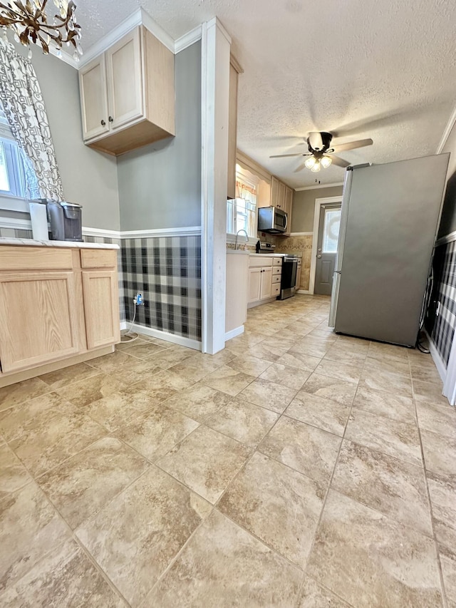 kitchen featuring stainless steel appliances, ceiling fan with notable chandelier, light brown cabinets, and a textured ceiling